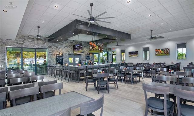 19712 The Place Blvd, Estero, FL 33928 On-site restaurant with spacious interior featuring a full-service bar with barstool seating, stone accent walls, integrated flat-screen televisions and tile flooring.
