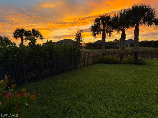19712 The Place Blvd, Estero, FL 33928 Expansive lawn area with mature palm trees and lush landscaping, enclosed by a black metal fence