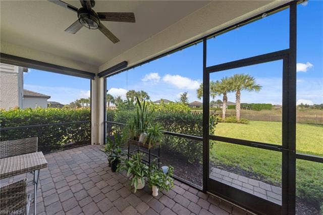 19712 The Place Blvd, Estero, FL 33928 Screened lanai featuring a ceiling fan, motorized privacy screens, paver flooring, and mature landscaping