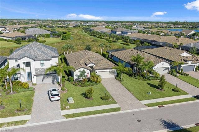 19712 The Place Blvd, Estero, FL 33928 Residential neighborhood with paved streets and sidewalks, featuring landscaped properties with green lawns and mature palm trees