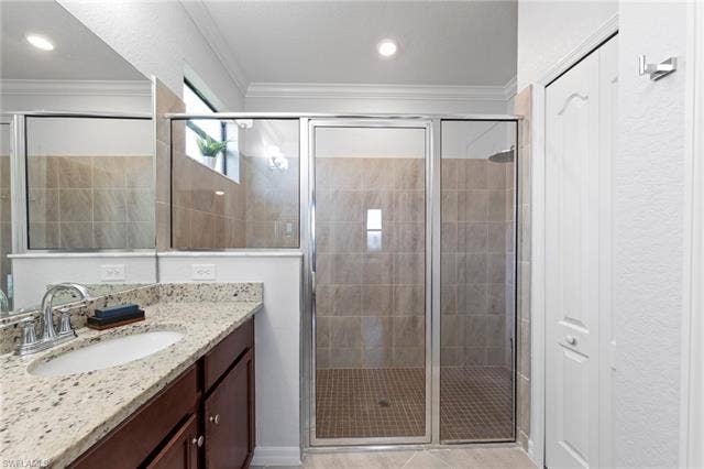 19712 The Place Blvd, Estero, FL 33928 Granite-finish countertop with an undermount sink, wood-finish cabinetry, a glass-enclosed extra-large shower with tiled walls and flooring