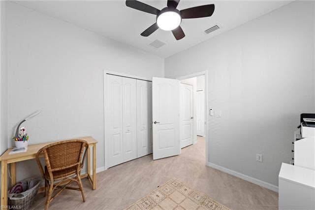 19712 The Place Blvd, Estero, FL 33928 Neutral wall paint, ceiling fan with integrated lighting, tiled flooring, bi-fold closet doors, and a solid interior door