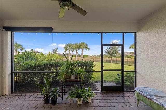 19712 The Place Blvd, Estero, FL 33928 Screened-in lanai featuring a ceiling fan, motorized privacy screens, brick paver flooring, and screen door