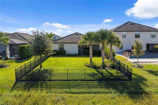 19712 The Place Blvd, Estero, FL 33928 Expansive backyard featuring a manicured lawn, perimeter fencing, and mature palm trees