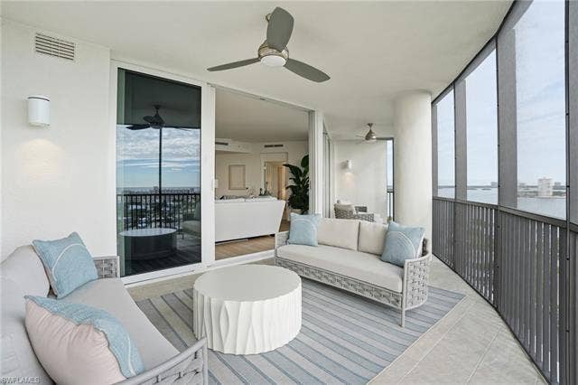 4142 Bay Beach Ln, #904, Fort Myers Beach, FL 33931 Sunroom featuring a wall of windows, an outdoor hangout area, plenty of natural light, a ceiling fan, and tile patterned floors - Virtually Edited Image