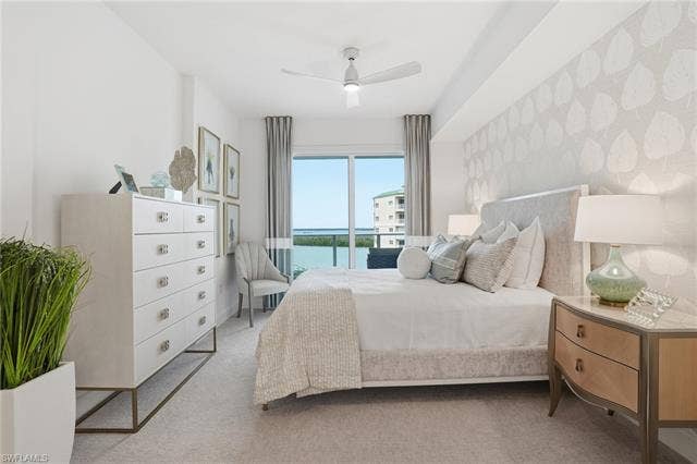 4142 Bay Beach Ln, #904, Fort Myers Beach, FL 33931 Bedroom featuring a water view, a ceiling fan, carpet, access to exterior, and wallpapered walls - Virtually Edited Image