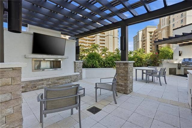 4142 Bay Beach Ln, #904, Fort Myers Beach, FL 33931 View of patio with a pergola, outdoor dining space, and an outdoor kitchen - Virtually Edited Image