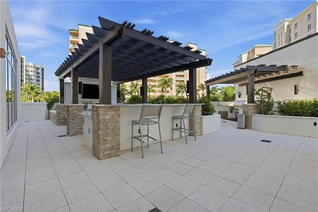 4142 Bay Beach Ln, #904, Fort Myers Beach, FL 33931 View of patio featuring area for grilling and a pergola - Virtually Edited Image