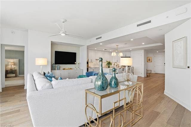 4142 Bay Beach Ln, #904, Fort Myers Beach, FL 33931 Living area featuring a tray ceiling, light wood-type flooring, recessed lighting, a ceiling fan, and a chandelier - Virtually Edited Image
