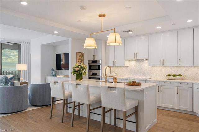 4142 Bay Beach Ln, #904, Fort Myers Beach, FL 33931 Kitchen with pendant lighting, backsplash, white cabinetry, recessed lighting, and a breakfast bar - Virtually Edited Image