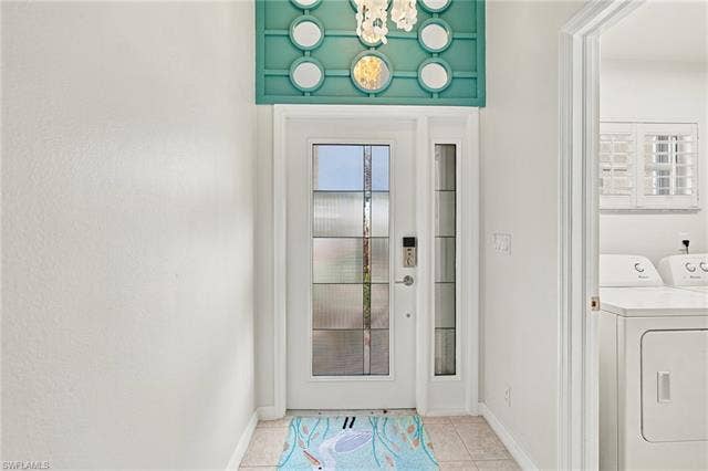 20052 Serene Meadow Ln, Estero, FL 33928 Entry door with decorative glass panels, transom window with accent trim, and tile flooring