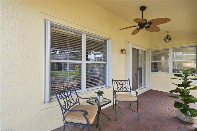 20052 Serene Meadow Ln, Estero, FL 33928 Covered patio featuring brick-finish flooring, a ceiling fan, and sliding glass doors