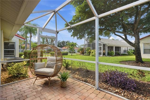 20052 Serene Meadow Ln, Estero, FL 33928 Screened patio with brick paver flooring, surrounded by landscaped garden beds, and a manicured lawn