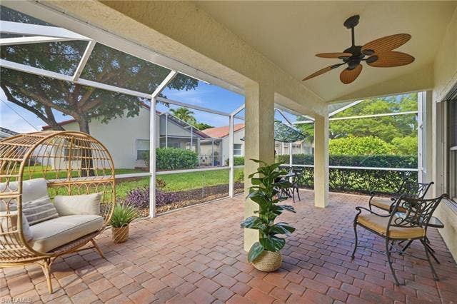 20052 Serene Meadow Ln, Estero, FL 33928 Screened patio featuring a ceiling fan, tiled flooring, structural columns, and a landscaped yard beyond