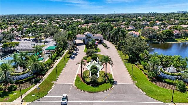 20052 Serene Meadow Ln, Estero, FL 33928 Gated community entrance featuring a decorative fountain, lush landscaping, and mature palm trees