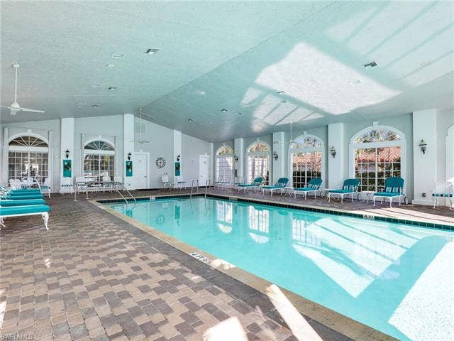 20052 Serene Meadow Ln, Estero, FL 33928 Indoor swimming pool with paver decking, vaulted ceilings, and multiple arched windows
