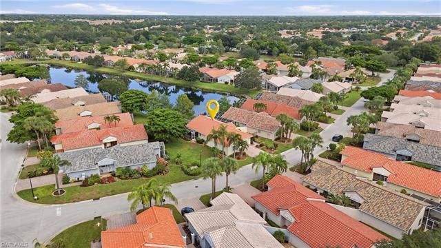 20052 Serene Meadow Ln, Estero, FL 33928 Residential neighborhood featuring mature landscaping, a central water feature, and a variety of roof styles