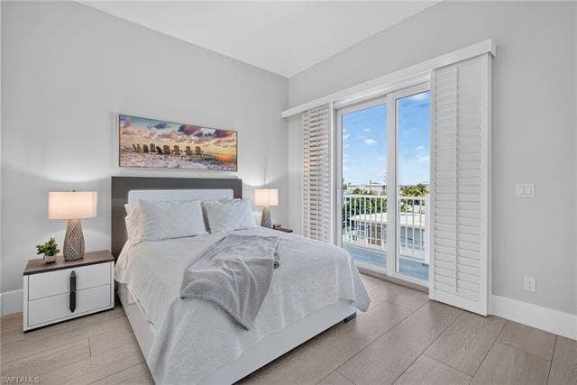 61 Mango St, Fort Myers Beach, FL 33931 Sliding glass door with white plantation shutters, light wood-finish flooring, and a balcony with white railings - Virtually Edited Image