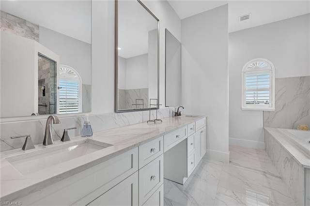 61 Mango St, Fort Myers Beach, FL 33931 Dual vanity with integrated sinks, white cabinetry, integrated makeup vanity, oversized mirrors, and a soaking tub - Virtually Edited Image
