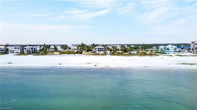 61 Mango St, Fort Myers Beach, FL 33931 Coastal residences fronting a white sand beach with clear turquoise waters - Virtually Edited Image