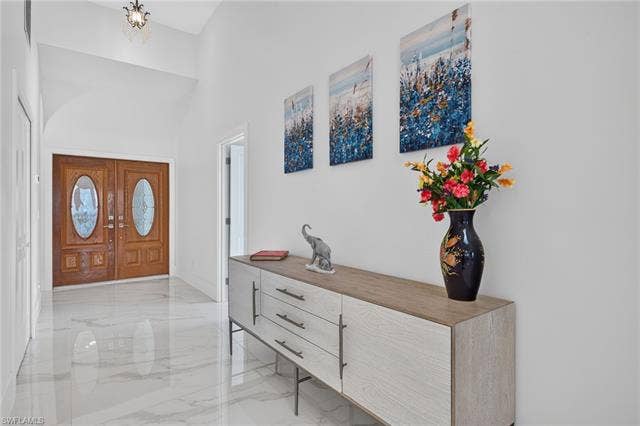 61 Mango St, Fort Myers Beach, FL 33931 Double entry doors with oval glass inserts, vaulted ceiling, and polished tile flooring - Virtually Edited Image