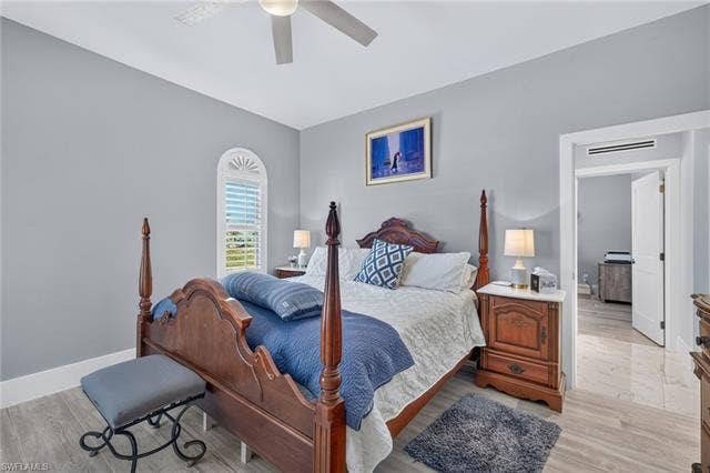 61 Mango St, Fort Myers Beach, FL 33931 Wood-finish flooring, recessed lighting, arched window with interior shutters, ceiling fan, and painted walls - Virtually Edited Image