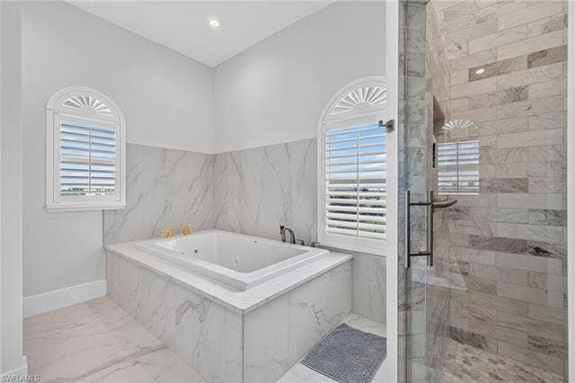 61 Mango St, Fort Myers Beach, FL 33931 Soaking tub with surrounding white marble-look tiling and integrated deck-mounted faucet - Virtually Edited Image