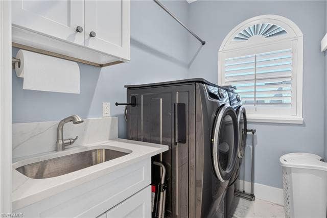 61 Mango St, Fort Myers Beach, FL 33931 White cabinetry with dark hardware, stainless steel sink with pull-down faucet, white countertop with integrated backsplash, and an arched window with plantation shutters - Virtually Edited Image