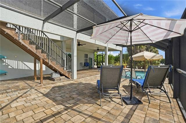 48 Fairview Blvd, Fort Myers Beach, FL 33931 View of patio / terrace with stairs, a sunroom, and a lanai - Virtually Edited Image