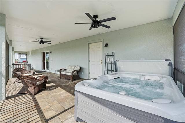 48 Fairview Blvd, Fort Myers Beach, FL 33931 View of patio / terrace with a ceiling fan, a hot tub, and a sunroom - Virtually Edited Image