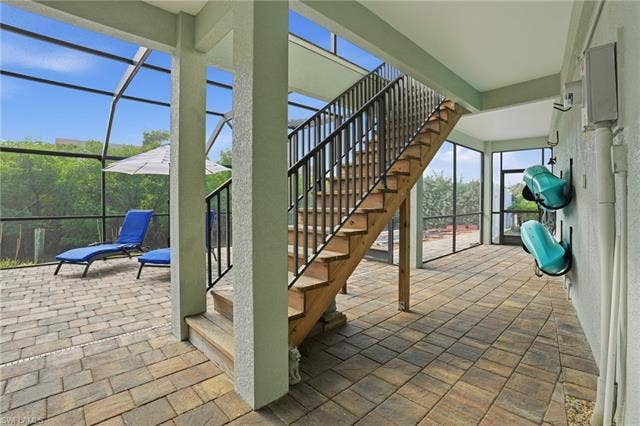 48 Fairview Blvd, Fort Myers Beach, FL 33931 View of patio featuring stairway, a lanai, and a sunroom - Virtually Edited Image