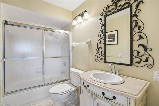 48 Fairview Blvd, Fort Myers Beach, FL 33931 Bathroom featuring bath / shower combo with glass door, vanity, and light tile patterned floors - Virtually Edited Image