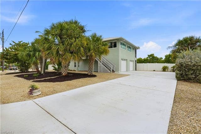 48 Fairview Blvd, Fort Myers Beach, FL 33931 View of front of house with concrete driveway, stucco siding, a garage, and stairs - Virtually Edited Image