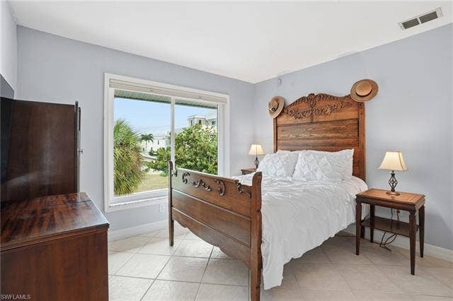 48 Fairview Blvd, Fort Myers Beach, FL 33931 Bedroom featuring baseboards and light tile patterned floors - Virtually Edited Image