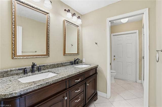 48 Fairview Blvd, Fort Myers Beach, FL 33931 Bathroom featuring double vanity and light tile patterned floors - Virtually Edited Image