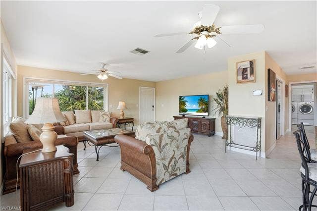 48 Fairview Blvd, Fort Myers Beach, FL 33931 Living area with washer and dryer, light tile patterned floors, and ceiling fan - Virtually Edited Image