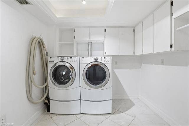 48 Fairview Blvd, Fort Myers Beach, FL 33931 Washroom featuring a tray ceiling, separate washer and dryer, and cabinet space - Virtually Edited Image