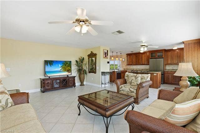 48 Fairview Blvd, Fort Myers Beach, FL 33931 Living area featuring light tile patterned floors and ceiling fan - Virtually Edited Image