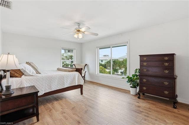 48 Fairview Blvd, Fort Myers Beach, FL 33931 Bedroom featuring light wood-style floors and a ceiling fan - Virtually Edited Image