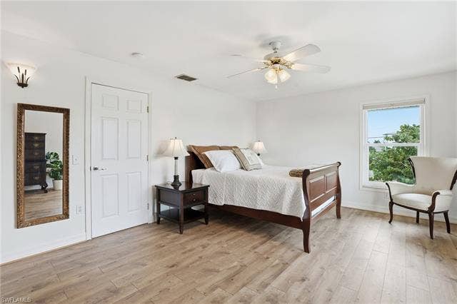 48 Fairview Blvd, Fort Myers Beach, FL 33931 Bedroom with light wood-type flooring and a ceiling fan - Virtually Edited Image