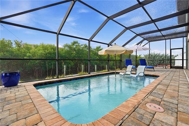 48 Fairview Blvd, Fort Myers Beach, FL 33931 Swimming pool featuring a lanai, a sunroom, and a patio - Virtually Edited Image