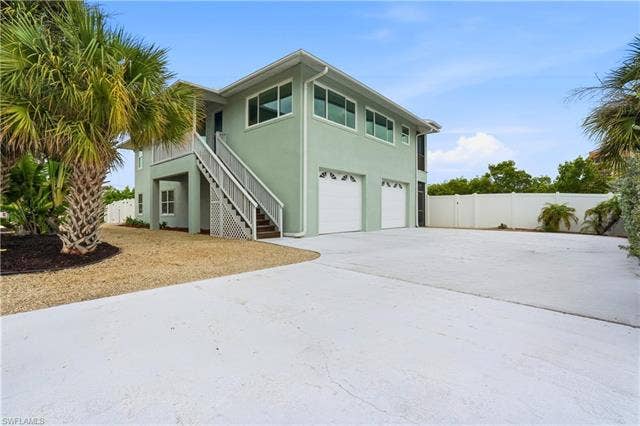 48 Fairview Blvd, Fort Myers Beach, FL 33931 View of front of house with stairs, a garage, stucco siding, concrete driveway, and a gate - Virtually Edited Image