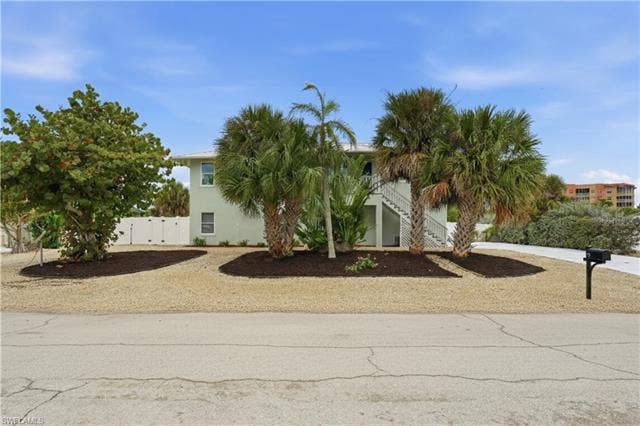 48 Fairview Blvd, Fort Myers Beach, FL 33931 View of property hidden behind natural elements with stairs, stucco siding, a gate, and driveway - Virtually Edited Image