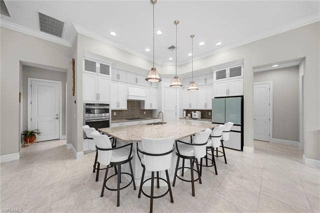 9796 Strike Ln, Bonita Springs, FL 34135 Spacious kitchen featuring an angular island with seating, white shaker cabinetry, recessed lighting, and stainless steel appliances