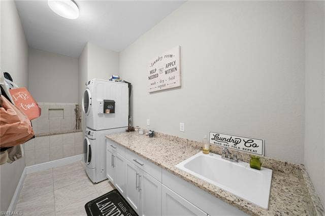 9796 Strike Ln, Bonita Springs, FL 34135 Built-in laundry sink, granite-style countertop, white cabinetry with silver hardware, light-toned floor tile, and a tiled utility ledge