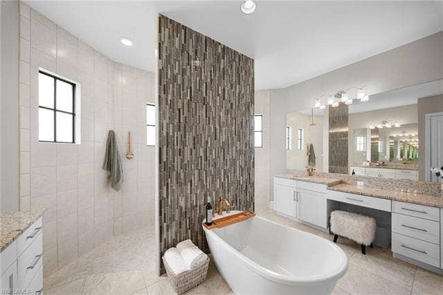 9796 Strike Ln, Bonita Springs, FL 34135 Freestanding soaking tub, dual vanity with granite countertops, separate shower with tile surround, and mosaic tile accent wall