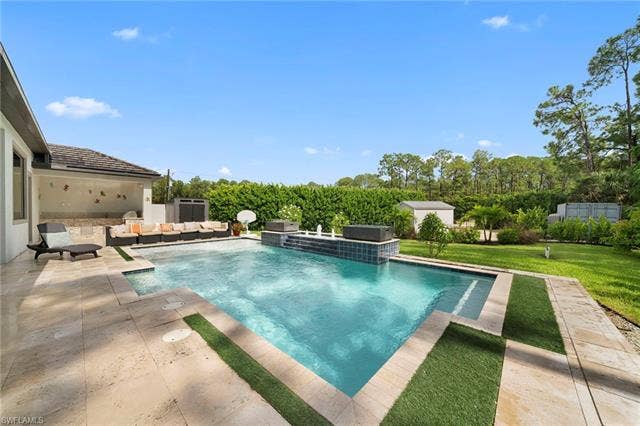9796 Strike Ln, Bonita Springs, FL 34135 Custom pool with an integrated spa, expansive stone patio, and a covered outdoor entertaining area