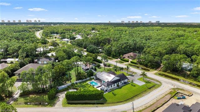 9796 Strike Ln, Bonita Springs, FL 34135 Aerial property showcasing a rectangular pool, solar panels, and extensive green space