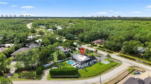 9796 Strike Ln, Bonita Springs, FL 34135 Expansive corner lot with mature trees, a private swimming pool, and solar panels