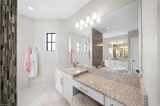 9796 Strike Ln, Bonita Springs, FL 34135 Spacious bathroom featuring a freestanding tub, dual vanity with granite countertops, and a large walk-in shower with mosaic tile accents